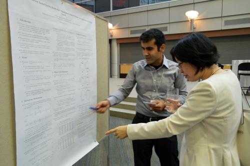 A professor and PhD candidate discuss research in front of a poster presentation at the CESG conference