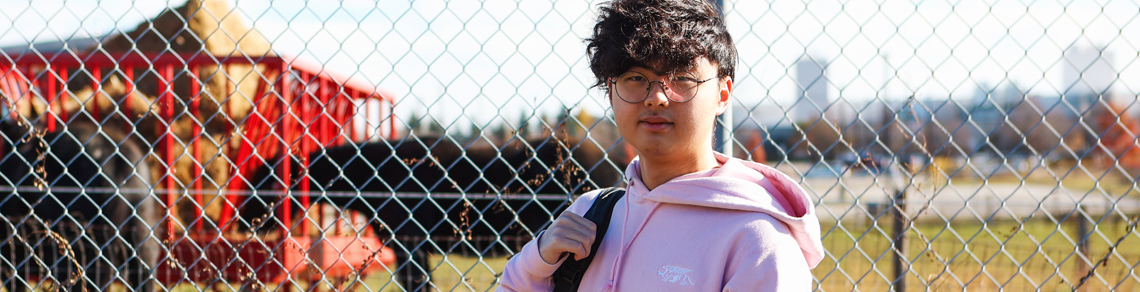 Oswin Lam posing for the camera with horses in the background
