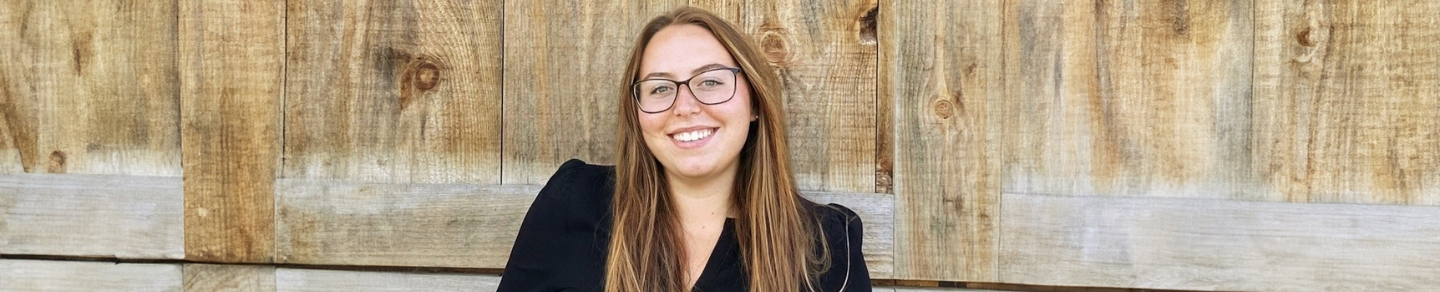 Brianna Giger standing outside near a wooden fence