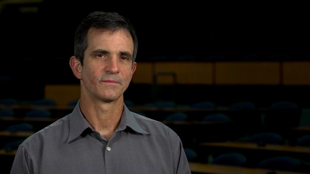 Alejandro Marangoni head shot sitting in dark lecture hall