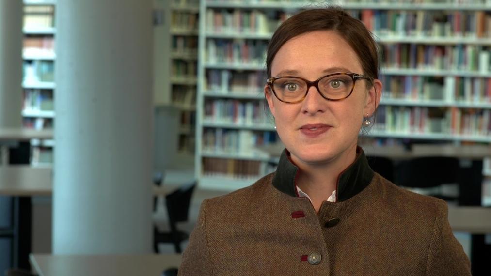 Christine Baes standing in front of shelves of books in a library