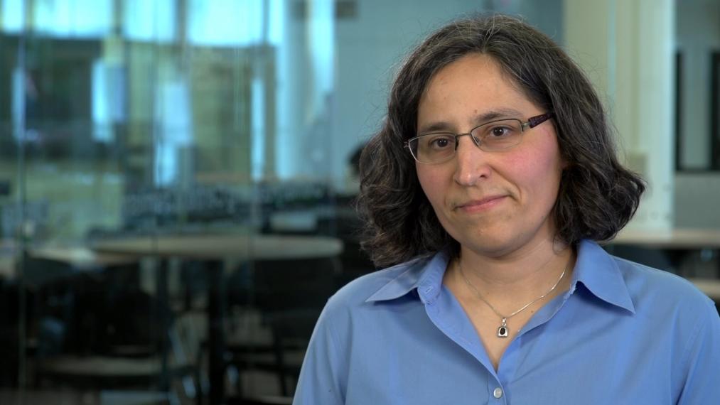 Emmanuelle in blue shirt in front of glass-walled classroom