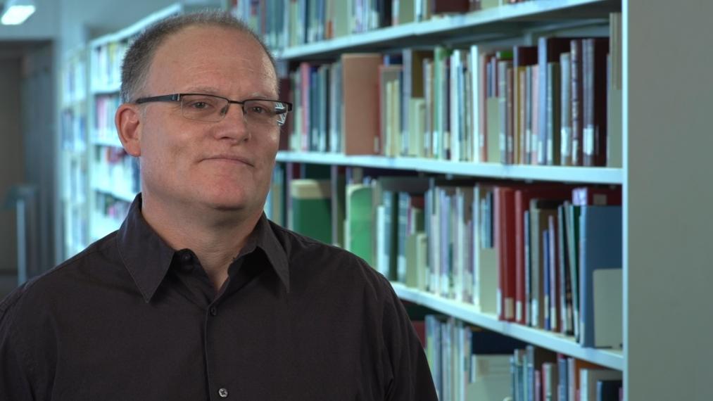 Hugh Earl standing in front of shelves of books