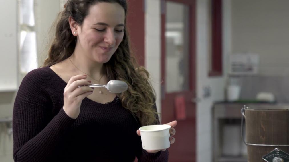 A student smiles while eating ice cream.