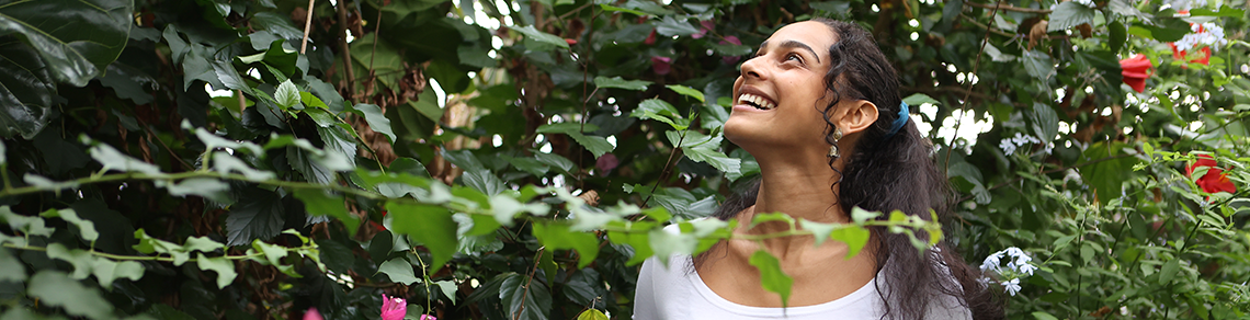 Crop Science student Clarke Picklyck standing in a greenhouse admiring the plants