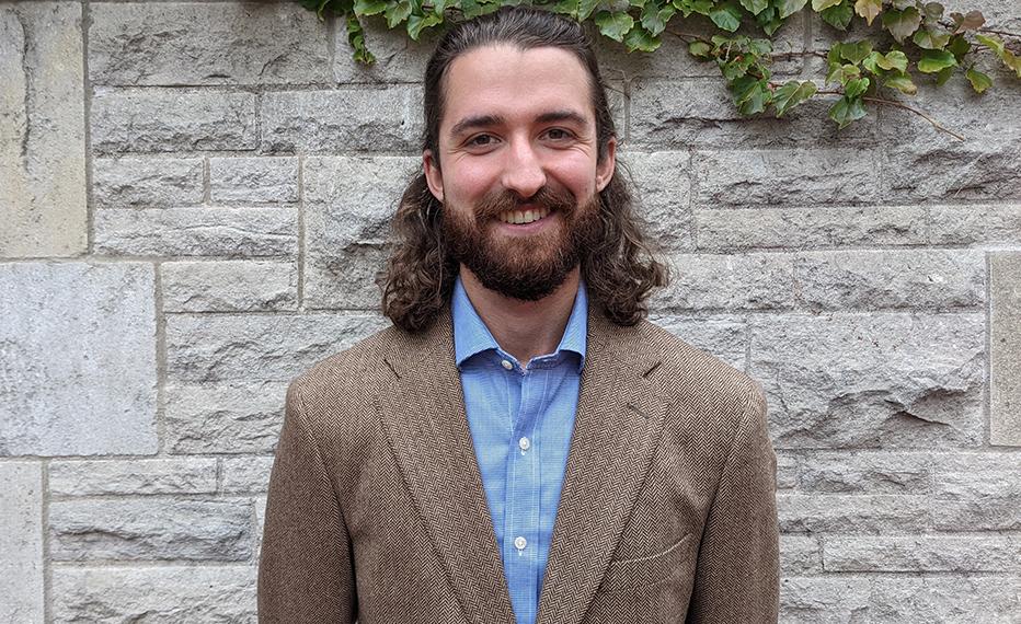 Head shot of Austin smiling in front of a building.