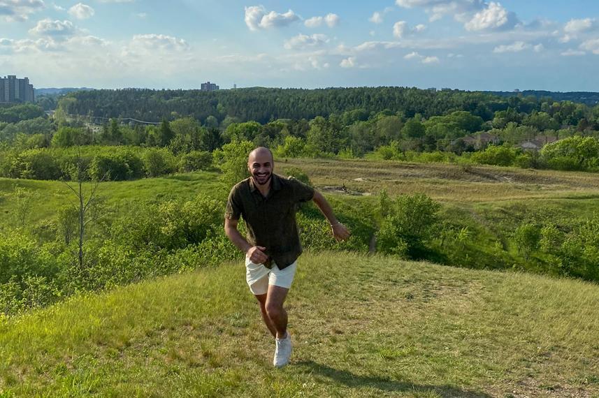 Ibrahim smiling with a field of greenery behind him