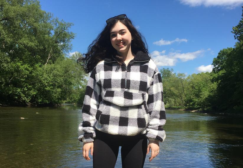 Madison standing in front of a river and trees.