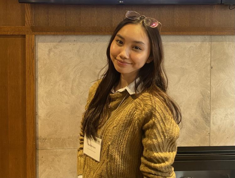 naifah posing for a photo with a green sweater on, wearing a lanyard with her name tag