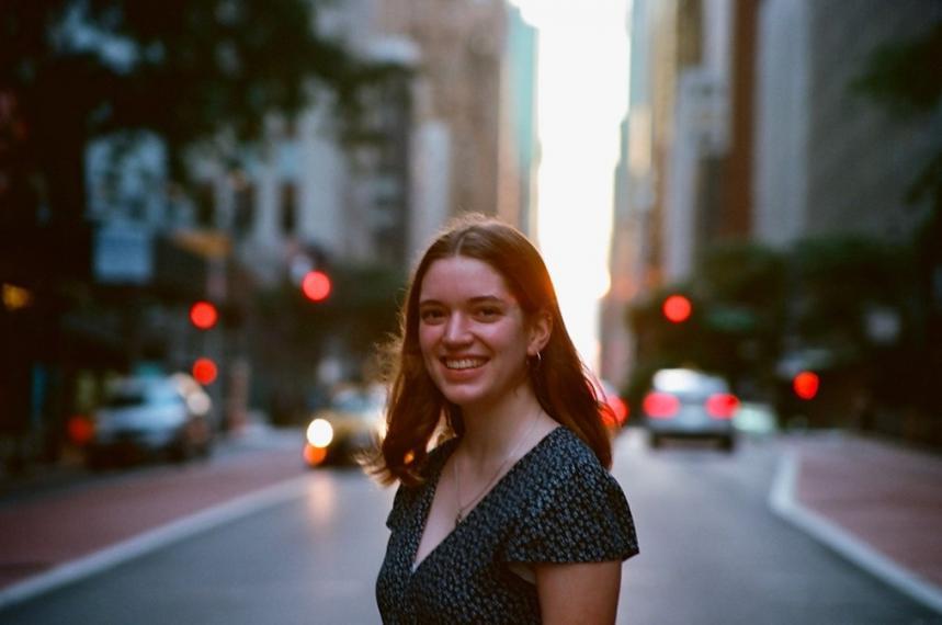 Oresta standing in a street with cars and buildings in the background