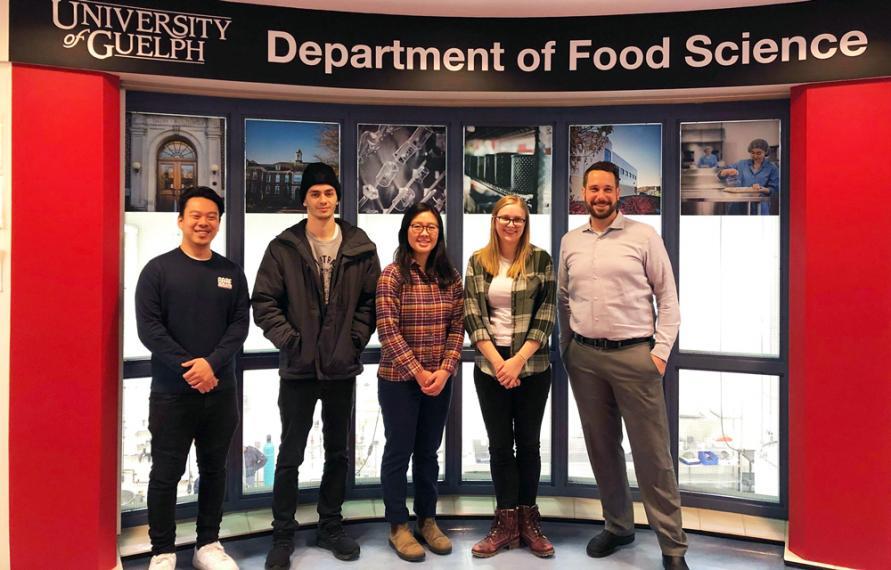 Team of students stands together with a large Department of Food Science banner behind them.
