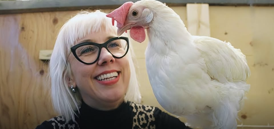 Alexandra Harlander smiling at a hen in a barn
