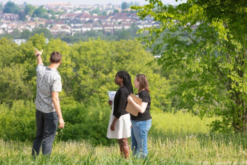 students looking out onto a city. standing in a field