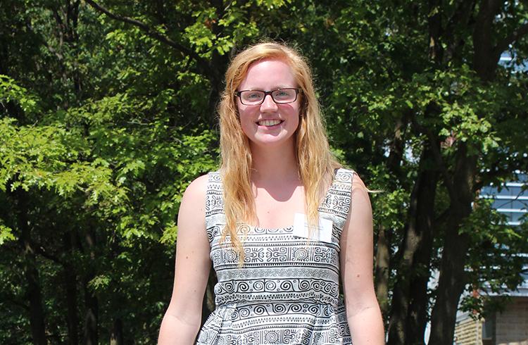 Alex wearing black and white top, outside in front of trees