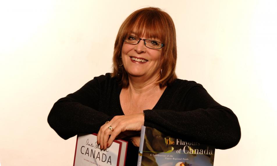 Anita Stewart smiles leaning on two cook books she authored