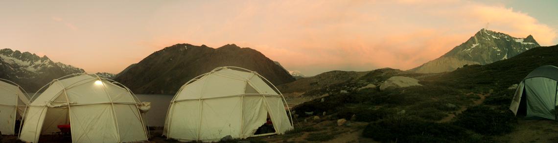 White tent structure on rocky terrain at dusk with pink sky