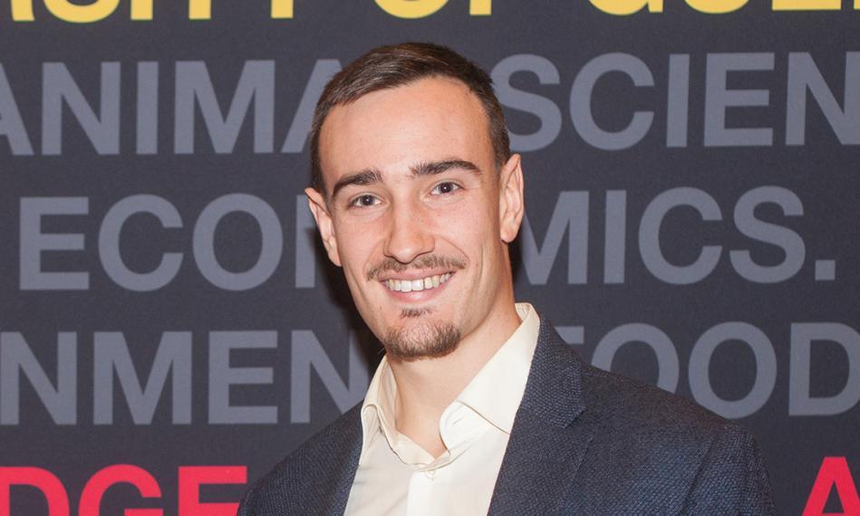 Cam Ogilvie headshot in front of photo backdrop