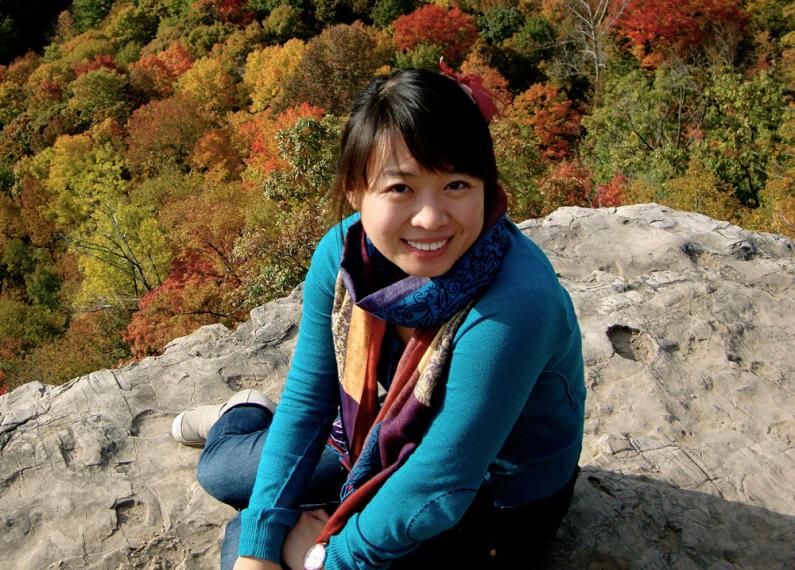 Claire sitting on a rock with fall coloured trees below