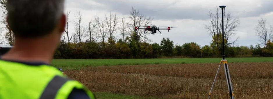 a person wearing hi-vis operating a drone over a field