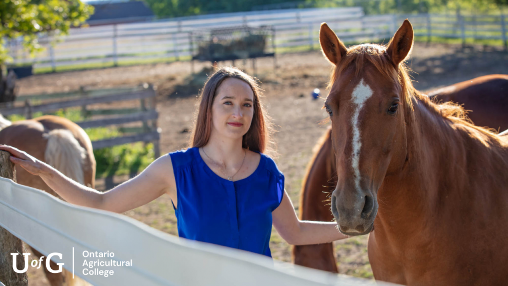 A woman stands next to a horse smiling while facing the camera.