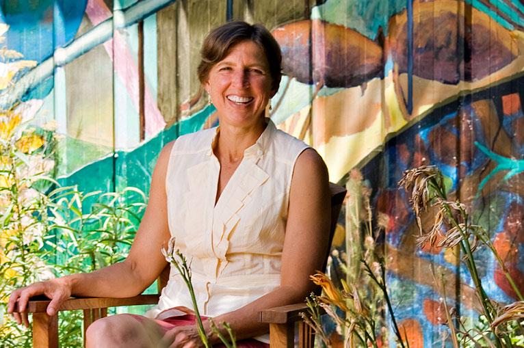 Pamela Ronald sits with bright mural behind her