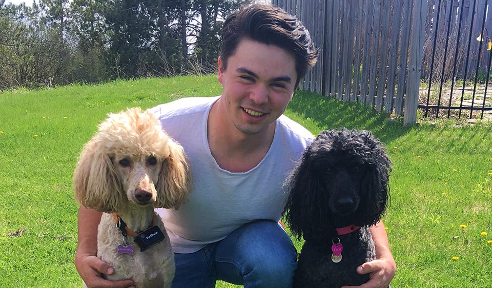 Thomas kneels and smiles with two dogs.