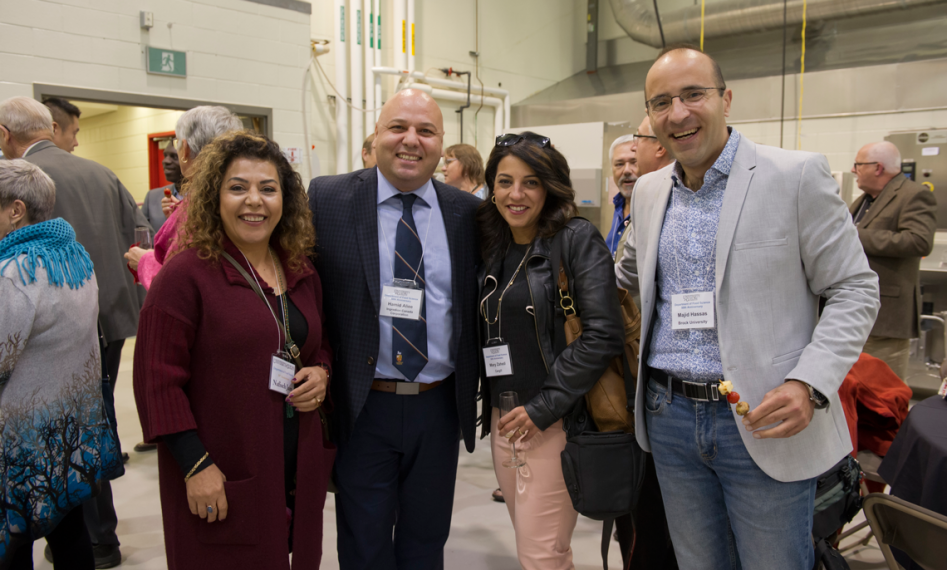 Four people stand together posing for photo in pilot plant