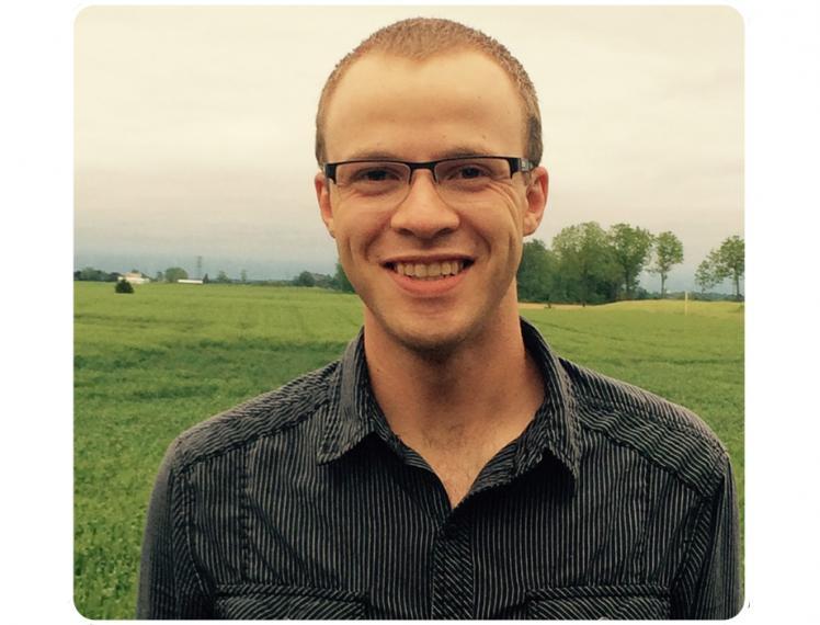 Joshua Dreise stands outside in front of a field.