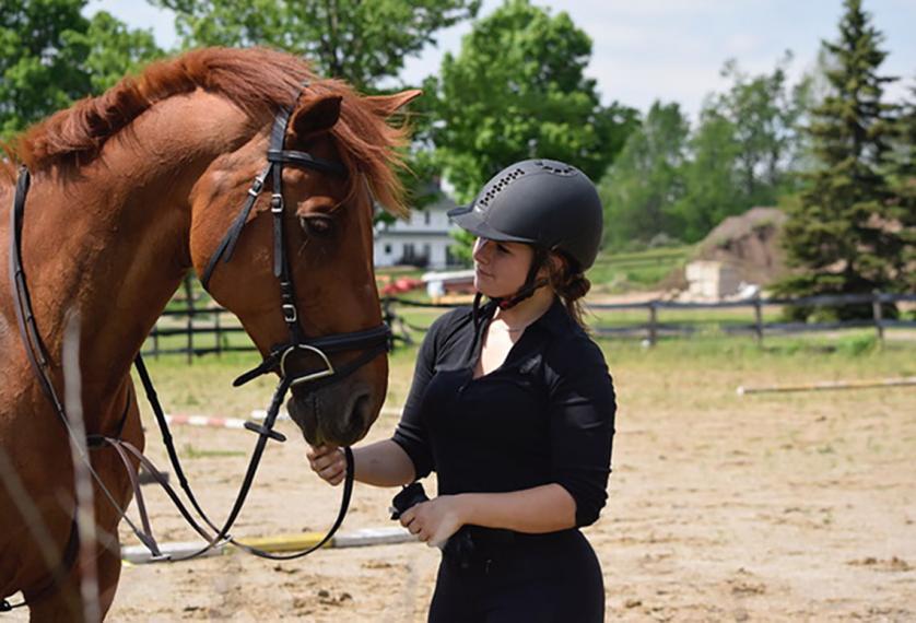 Julia stands beside and looks at brown horse