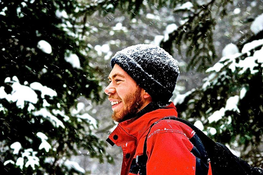 Kevin in snowy evergreen forest wearing toque and red jacket