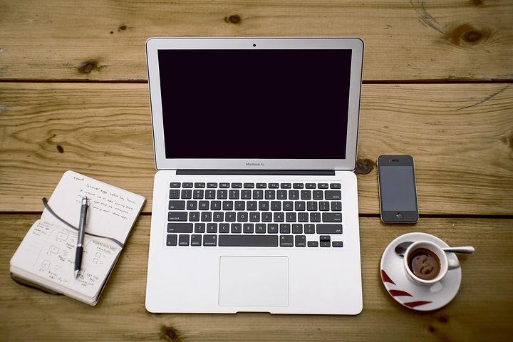 A work station with a laptop, cellphone and notepad