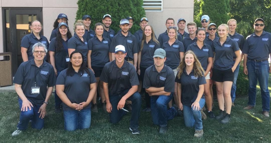 Group of 24 students stand together outside wearing matching polo shirts.