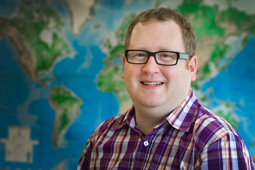 Head shot photo of Ryan Gibson in front of large blue and green map