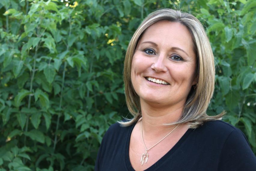 Sheri Longboat smiling in front of green leaves of tree