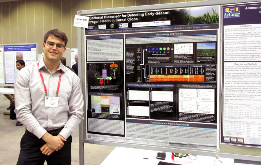 Travis standing with large poster presentation on his research
