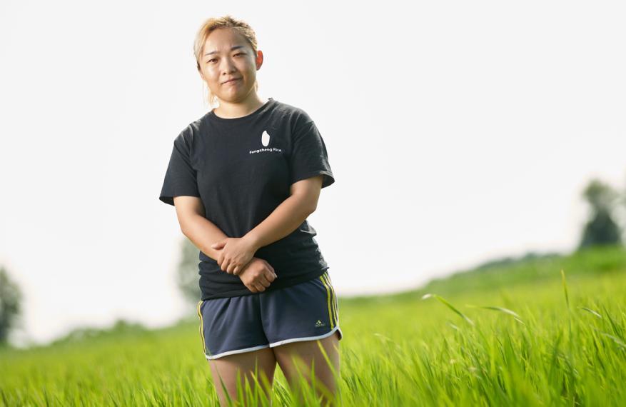 Wendy standing in rice field with green rice plants all around