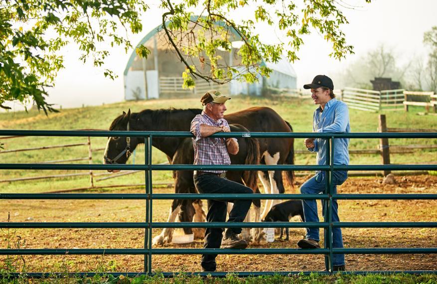 Wyatt McWilliams snd Josh Moran lean on a farm fence post