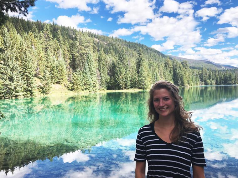 Annet Laan standing in front of a body of water and forest while visiting the west coast.