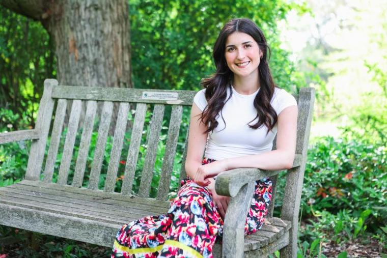Marah Laforge sitting on a wooden bench and smiling for the camera