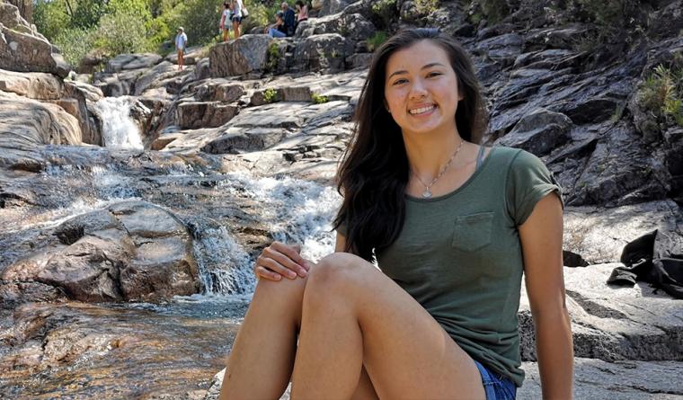 Head shot of Vanessa, sitting in front of a small waterfall at a conservation area.