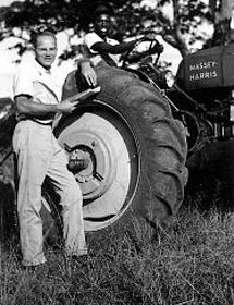 Black and white photo of Allen Thomas Knight leaning against tractor tire.