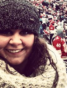 Headshot of Erin Genge wearing hat and scarf at hockey game.