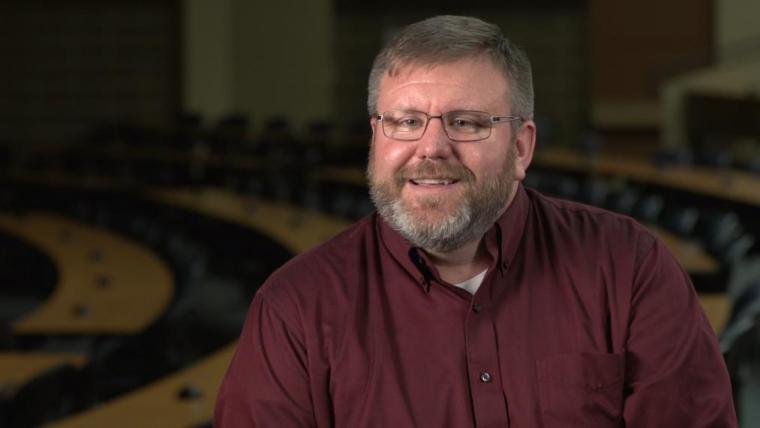 Prof. Eric Lyons headshot sitting in dark lecture room