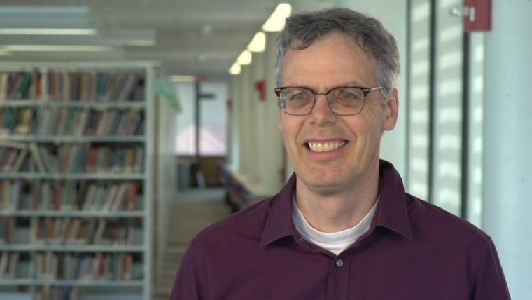 Francois smiling with bookshelves behind him