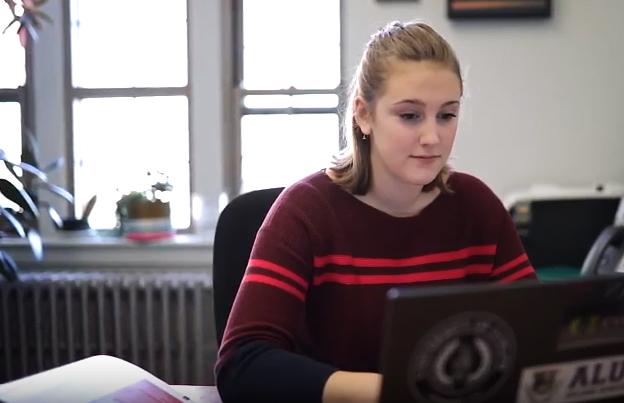 Michelle sits at a desk working on a laptop.