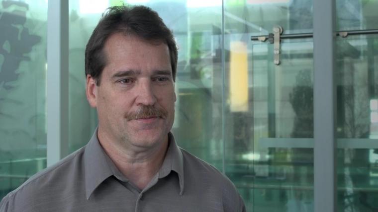 Head shot photo of Paul Sibley in front of green reflective glass