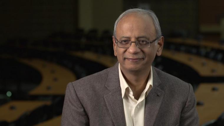 Head shot photo of Prof. Praveen Saxena in dark lecture room