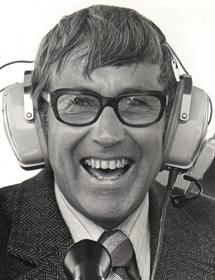 George Atkins wears headphones at a microphone.