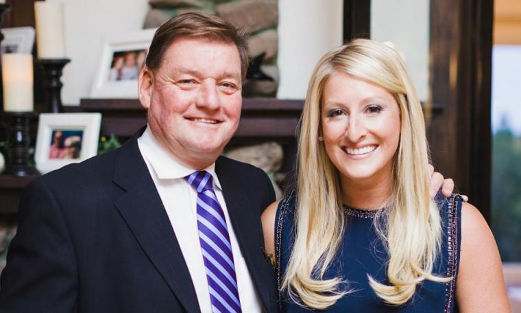 Hugh and Cassandra Loomans stand close together smiling