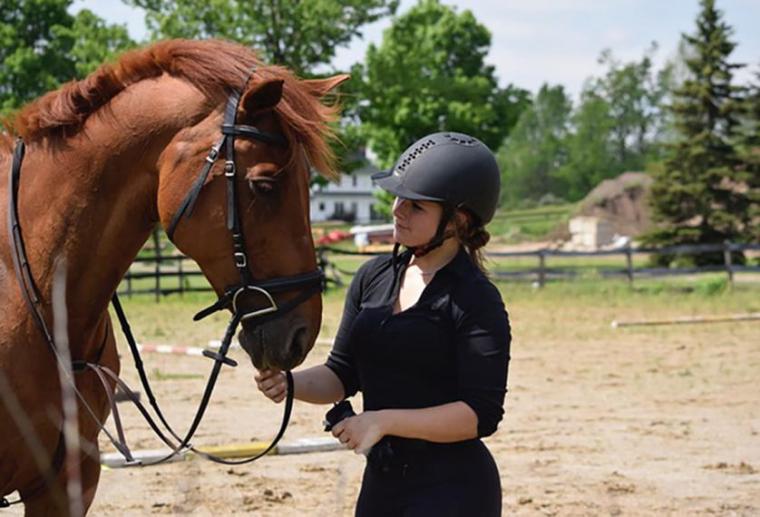 Julia stands beside and looks at brown horse